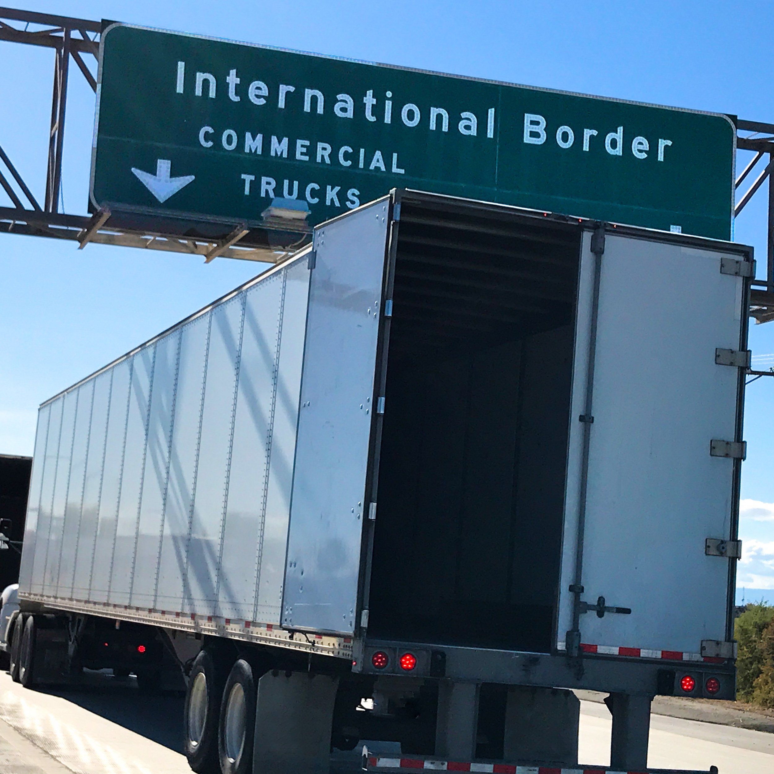 A white semi-truck sits in the Commercial Rental Truck line at the International Border.