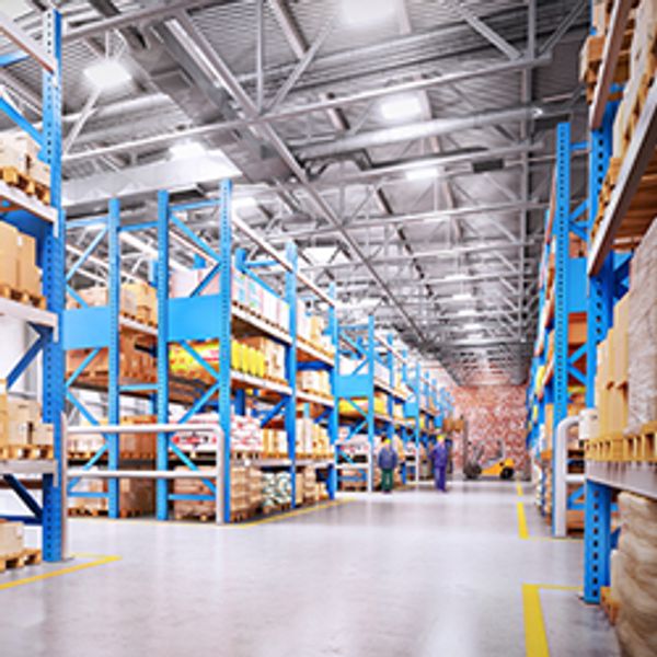 A wide shot of two workers standing in the middle of a warehouse.